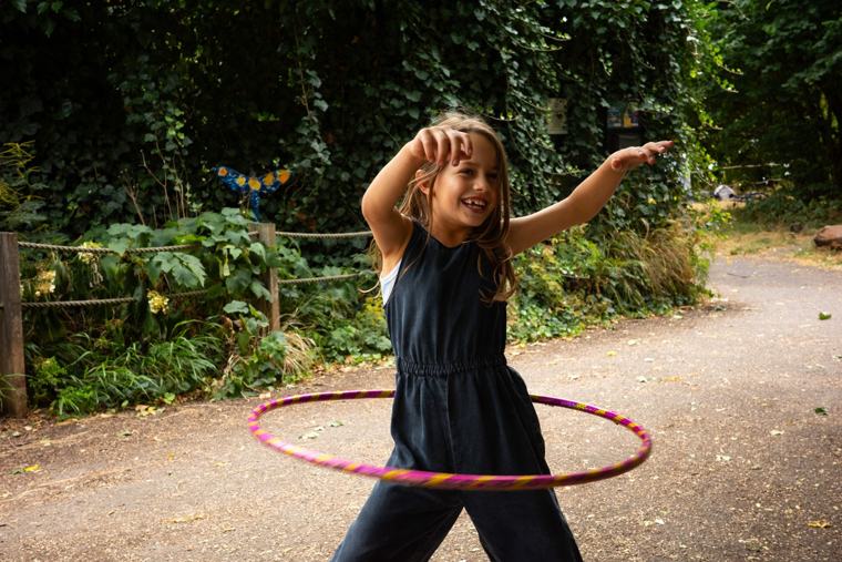 A child playing outside with a hula hoop