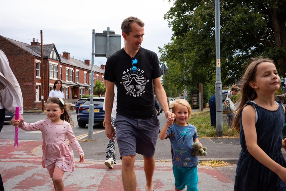 Parents and children walking to school together along a residential street